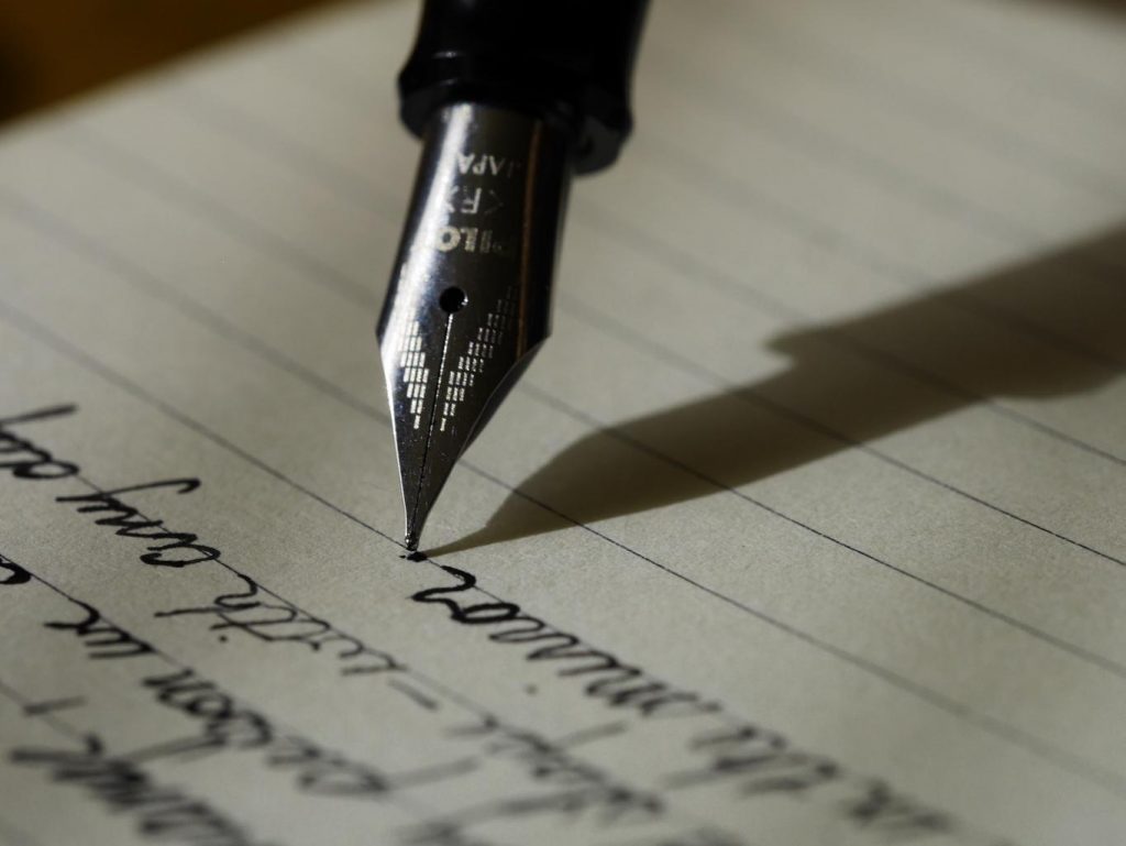 Image of a pen on a page, writing. 